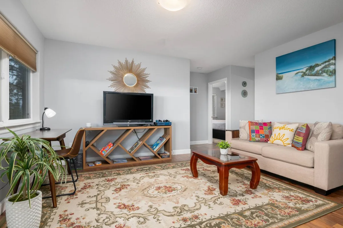 This cozy living room scene shows a sofa, coffee table, television, and decorative artwork. The space is welcoming—ideal for families and pets to spend time together unwinding or playing games after a day of exploration.