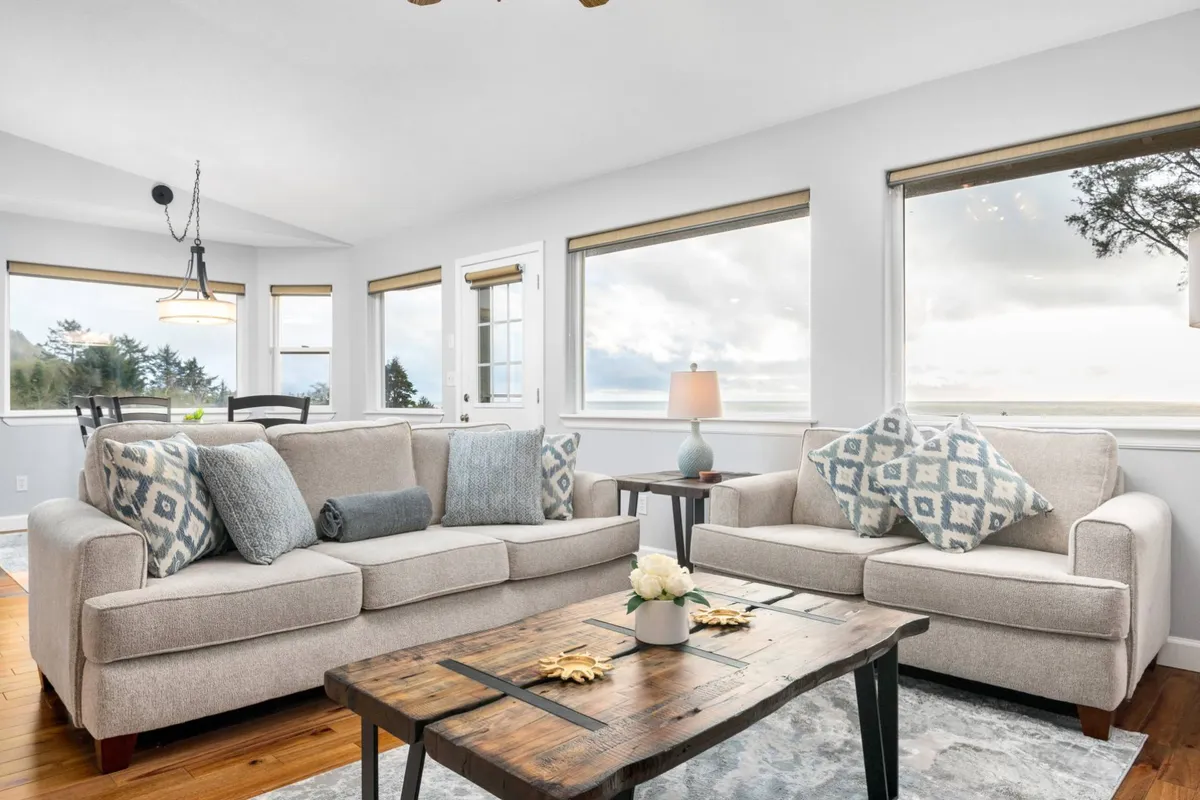 A comfortable living room with a sofa, coffee table, and large windows allowing natural light to pour in. The space feels welcoming for families to relax, play games, or gather after outdoor adventures.