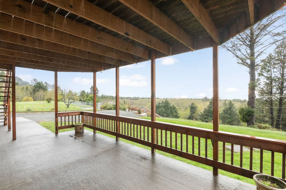 This image showcases a spacious wooden patio with a sturdy railing, offering expansive views of the surrounding natural landscape. The open-air setting is peaceful and inviting, ideal for taking coffee breaks, working outdoors, or enjoying tranquil moments in nature. The photo is bathed in soft daylight, emphasizing the connection between indoor productivity and outdoor relaxation.